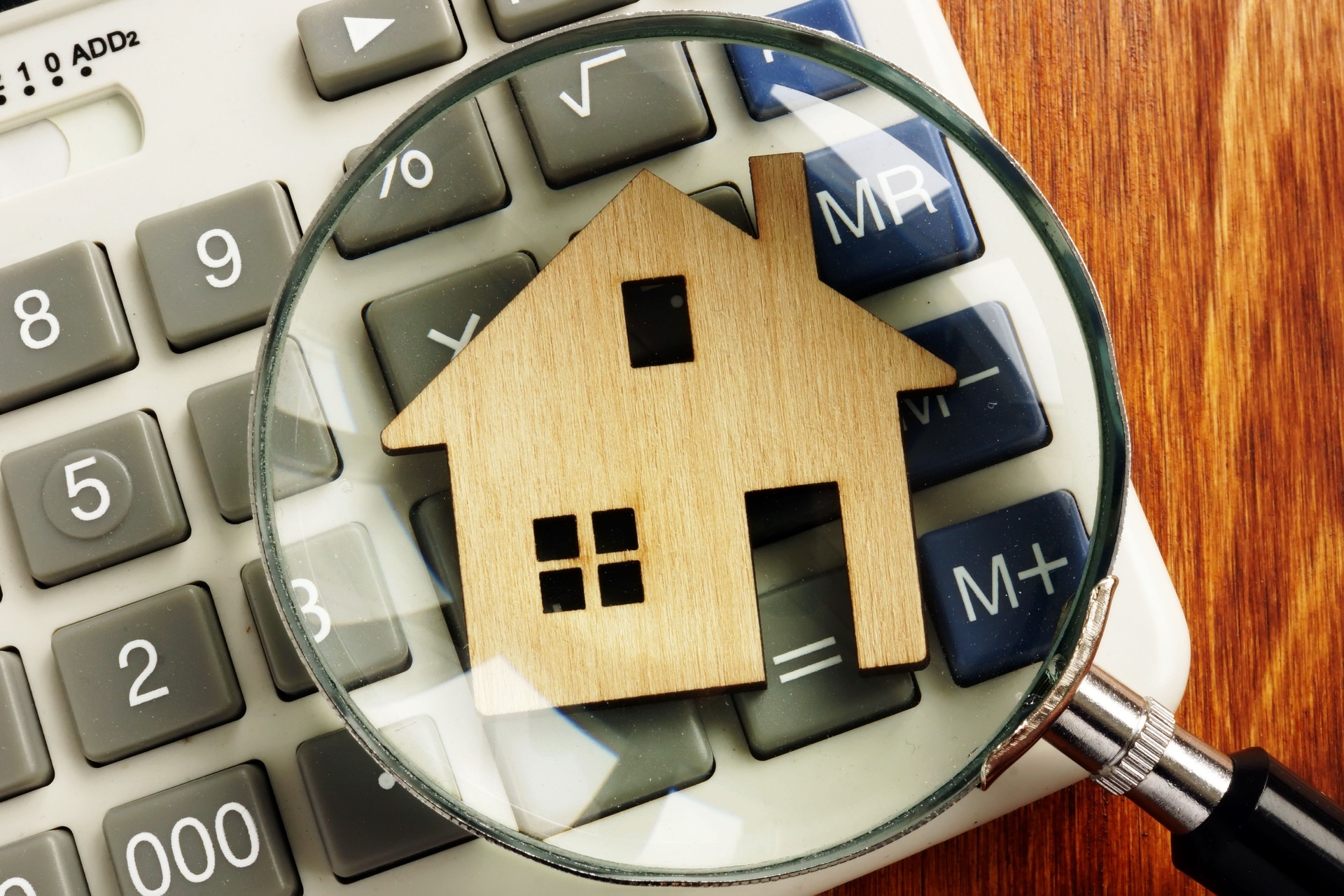 House value. Model of home, calculator and magnifying glass.