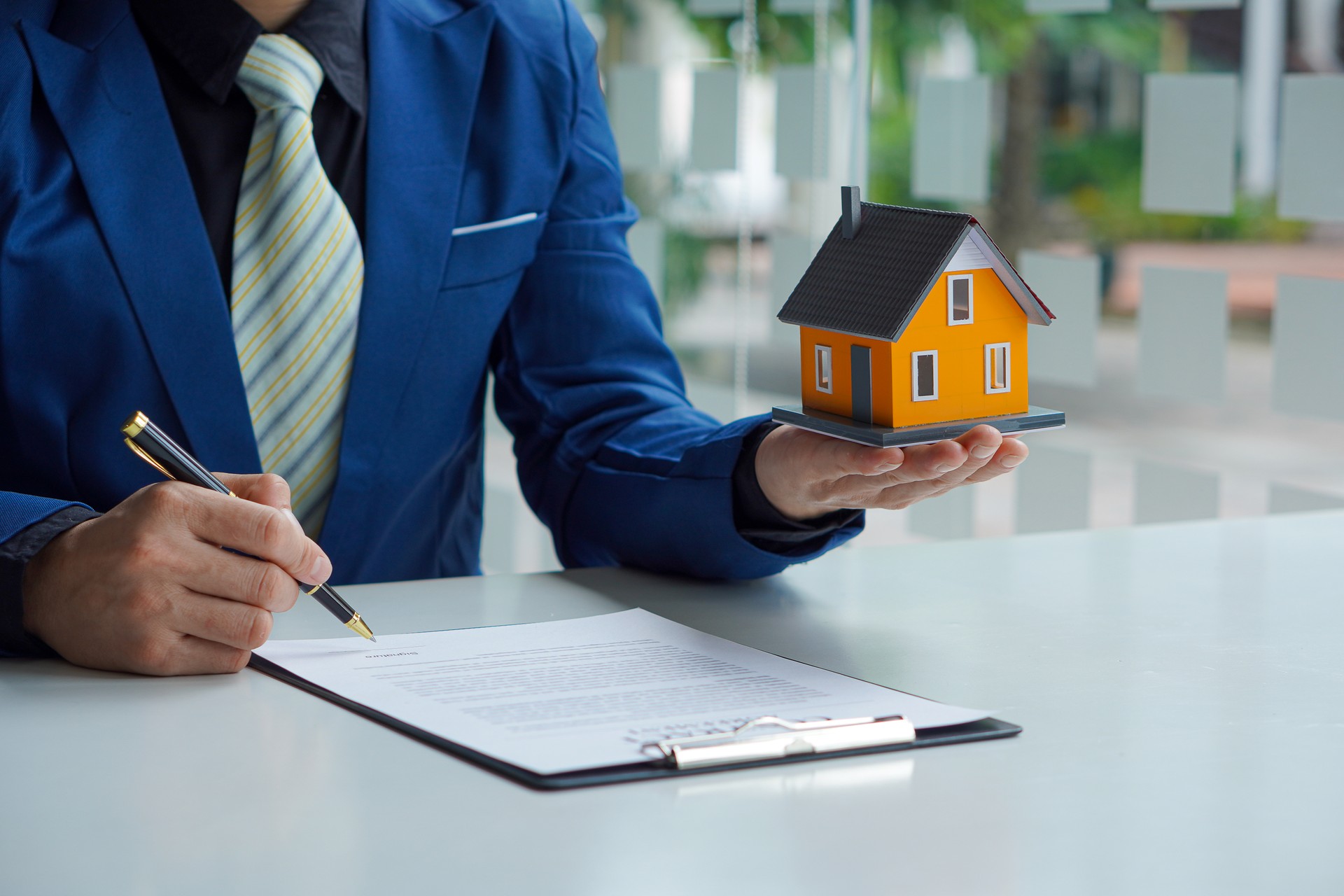 A real estate agent holds a small home and delivers it to the customer after the contract is complete in agreeing to buy a home and lease the concept.