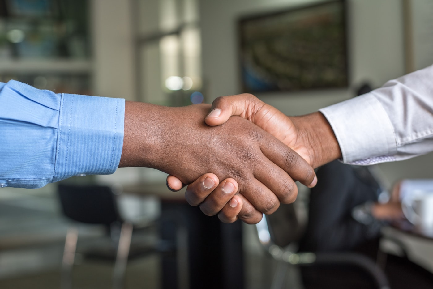 Two people shaking hands over a signed investment agreement
